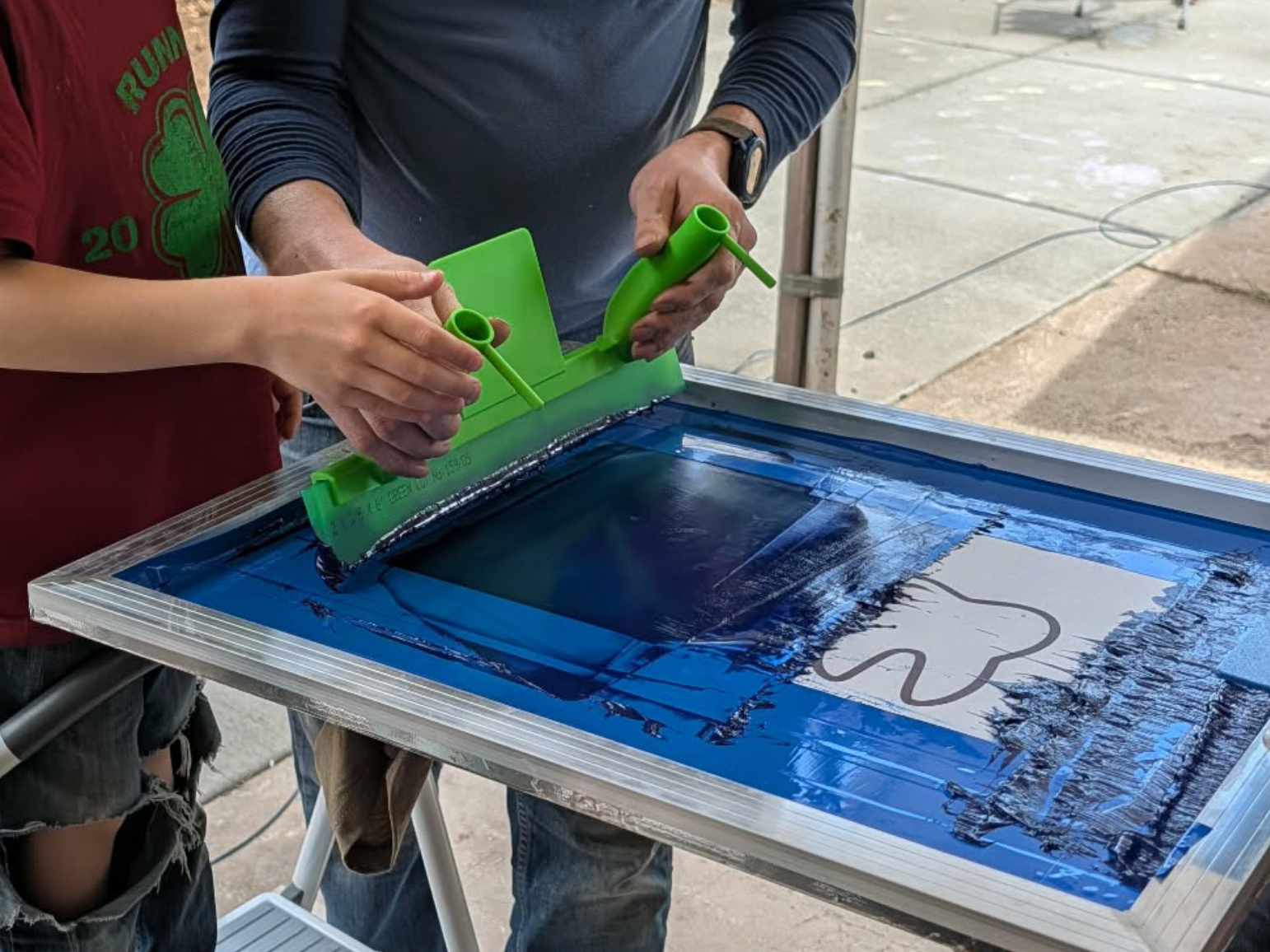 Guest pulling squeegee on press to book live screen printing in Ogden with Canyon Canvas